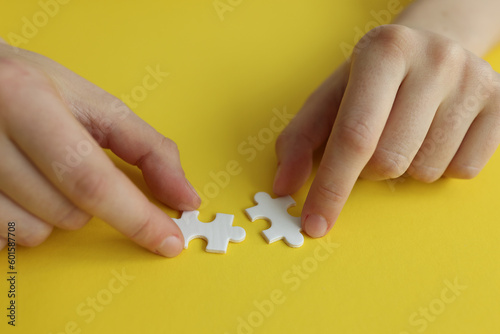 Female hands assemble white jigsaw puzzle pieces together