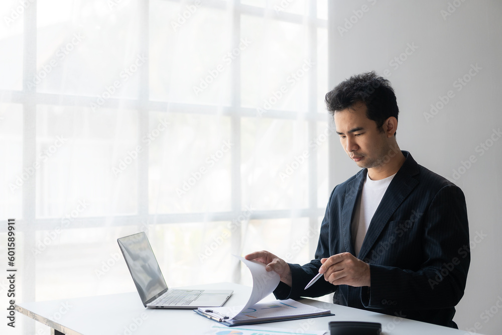 Young asian businessman planning analyzing financial data charts and graphs and successful business laptop Young asian businessman planning analyzing financial data charts and graphs and successful business laptop