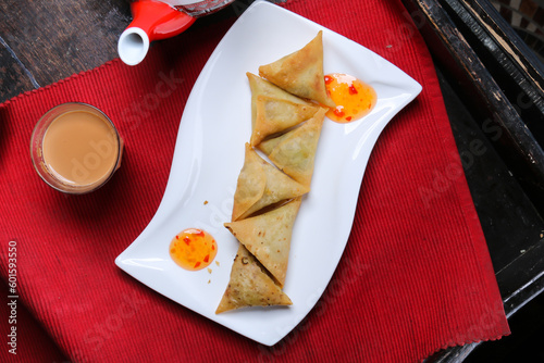 Samosa, sambosa, with sauce, tea and teapot served in dish isolated on red mat top view on table arabic food photo