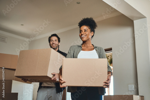 Happy couple, real estate and moving in with boxes for renovation, investment or relocation in new home. Interracial man and woman realtor owner carrying box in house, move or property loan together