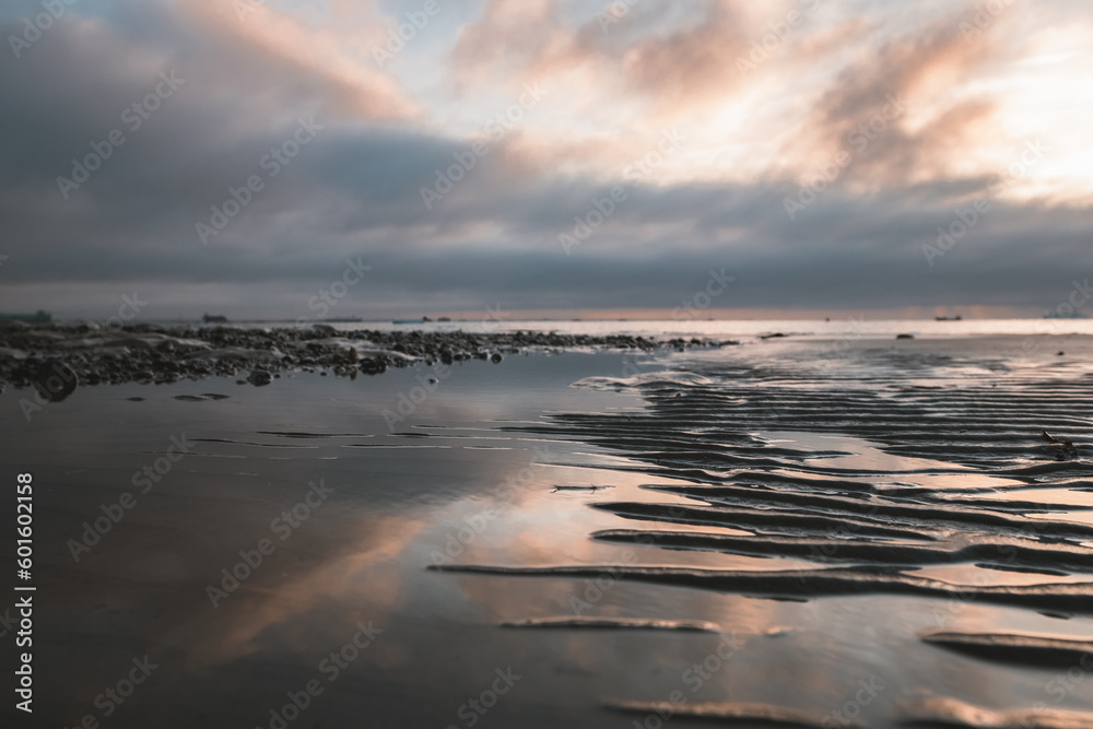 A sunset shot of calm waves washing onto the wert sand at a beach