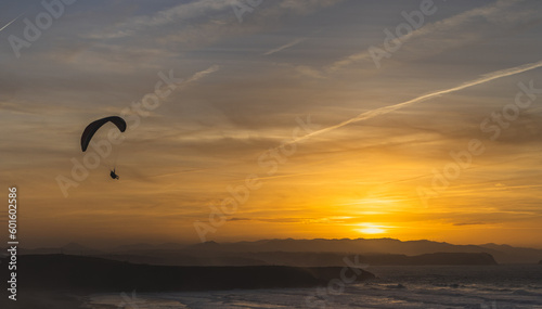 Nice sunset with people paragliding over the sea