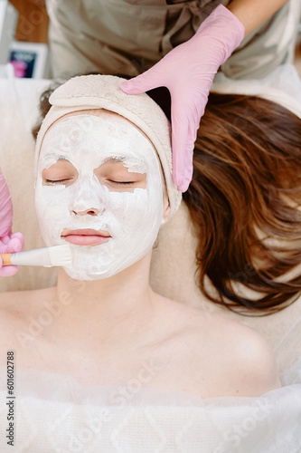 A cosmetologist in pink gloves on top applies a mask to a client, makes procedures in a spa or salon. Skin care, cosmetology and beauty.