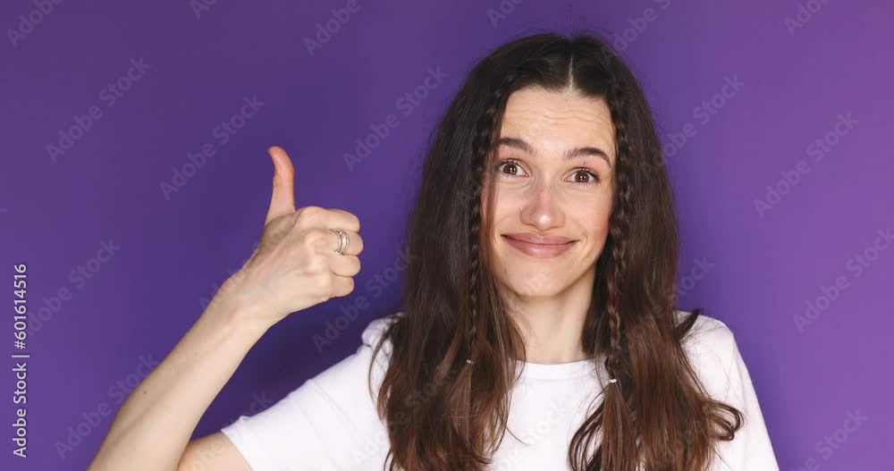 Young woman in white long sleeve making good-bad sign isolated on purple background. Girl make choice, or makes a decision thumb up or thumb down, like or dislike, yes or no. Girl shrugs, not sure.