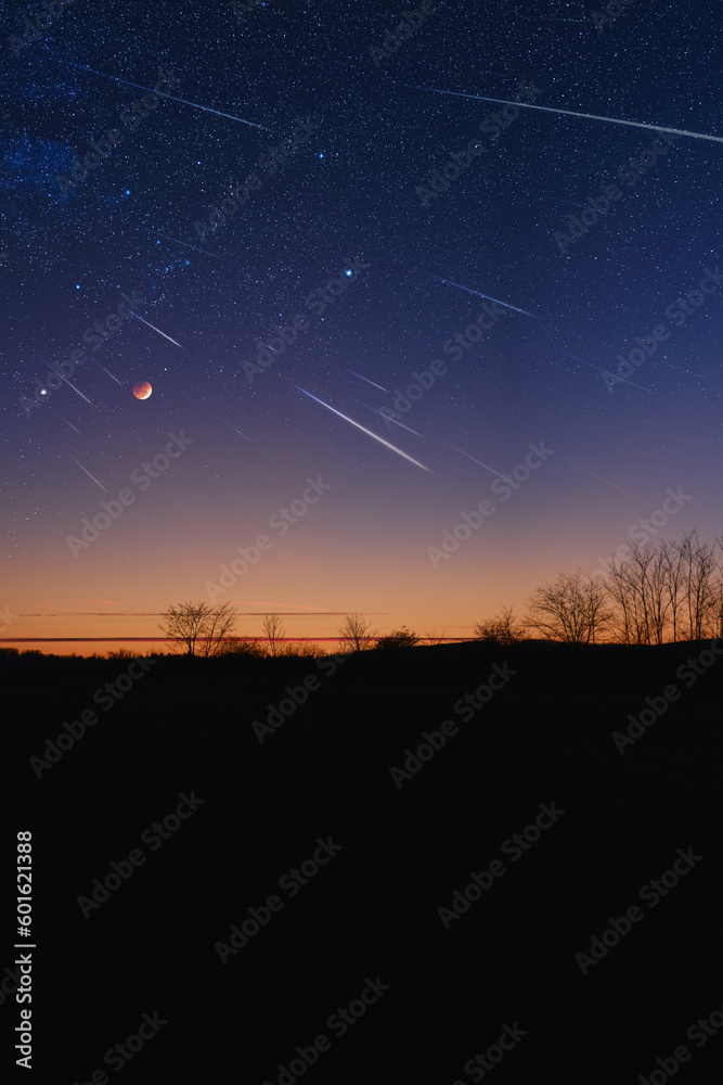 Silhouette of a countryside with Milky Way starry skies, meteor shower and crescent Moon.