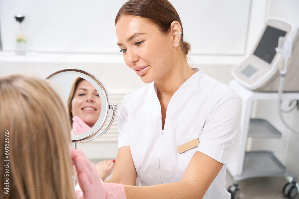 Female cosmetologist at the workplace consults female patient in bathrobe Female cosmetologist at the workplace consults female patient in bathrobe