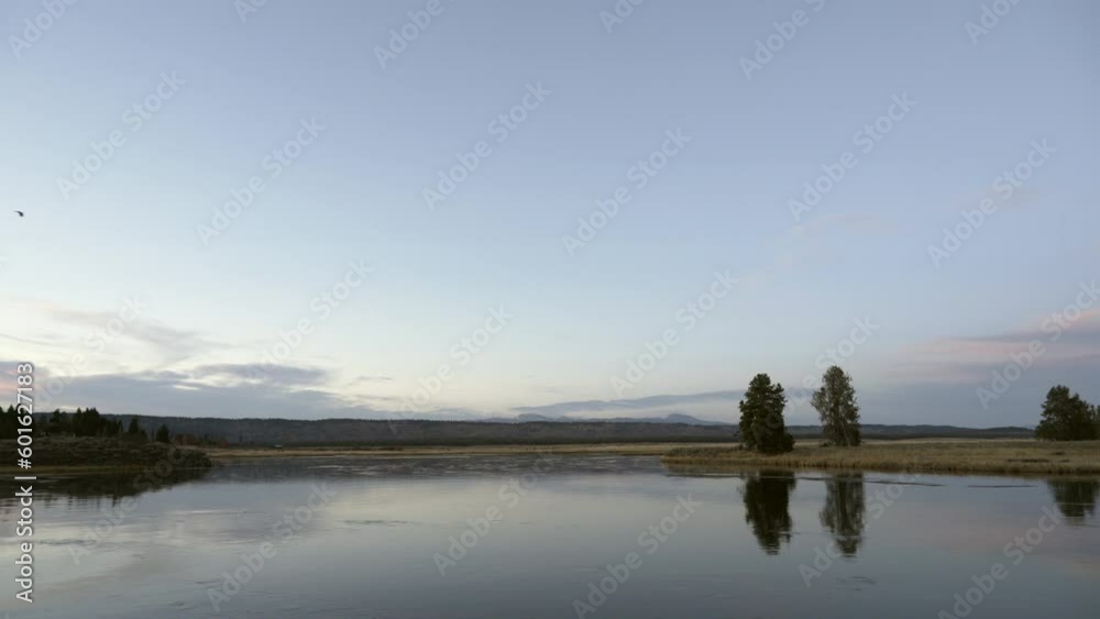 Eagle flies over calmly flowing river in Idaho at dusk in autumn Eagle flies over calmly flowing river in Idaho at dusk in autumn