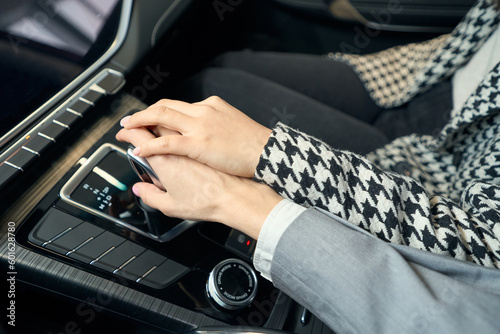Two women's hands in suits on automobile gearbox