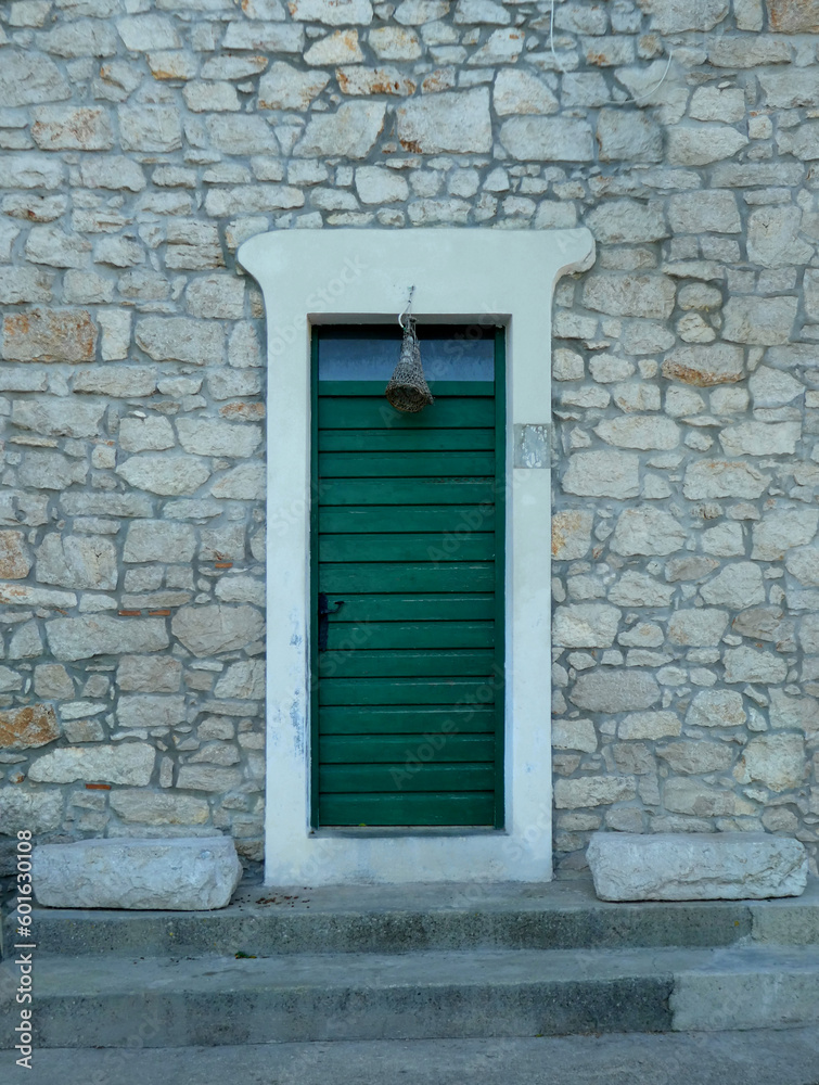 green door with white frame against stone brick wall on old house with steps