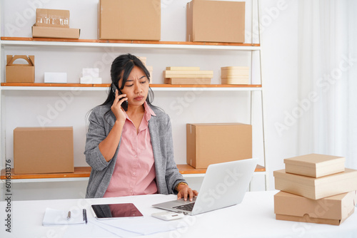 Photo of asian business woman talking on the phone, arguing with a client or customer, solving a business problem © Illhamt
