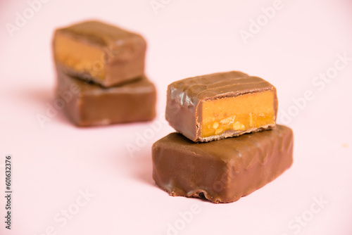 Sweet chocolate bar with salted caramel macro on pink paper background with copy space