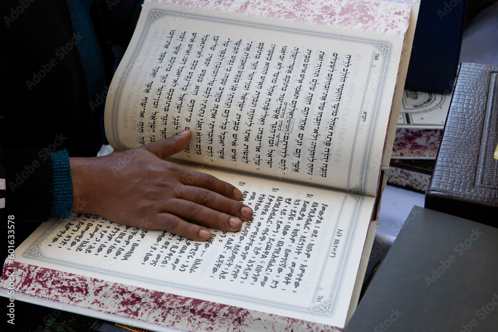 Obraz premium Jewish Ethiopian man reading from the Jewish bible or Torah in Amharic.