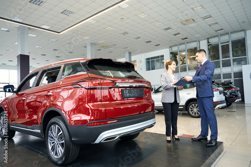 Woman and man signing documents in car dealership