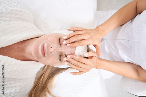 Specialist cosmetologist applies a rejuvenating mask to a womans face