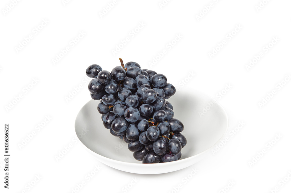 Branch of ripe blue grape on plate isolated white background. Juicy grapes with copy space Branch of ripe blue grape on plate isolated white background. Juicy grapes with copy space