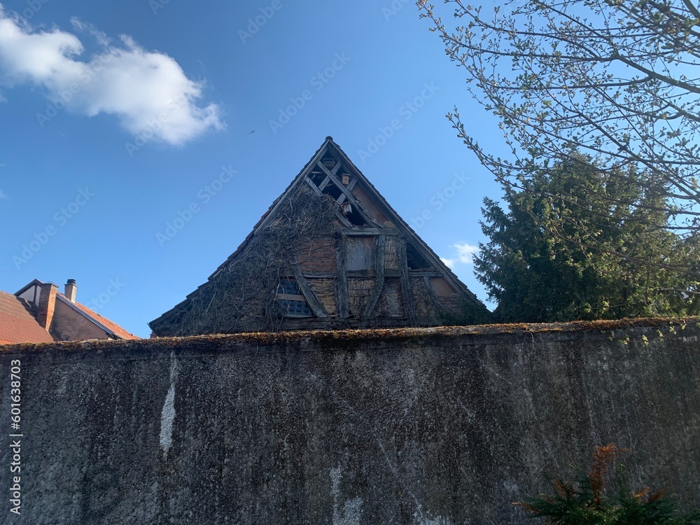 Altes Scheunendach hinter einer Mauer vor blauem Himmel