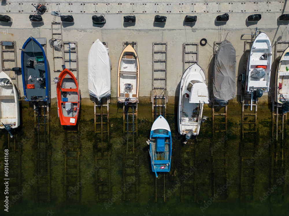 aerial view of a serene dock in the sea, with several fishing boats ...