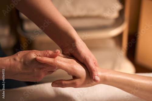 Qualified massotherapist giving hand massage to patient