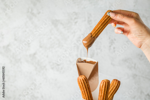 Foto Woman taking churros from a cone and dipping it in chocolate sauce