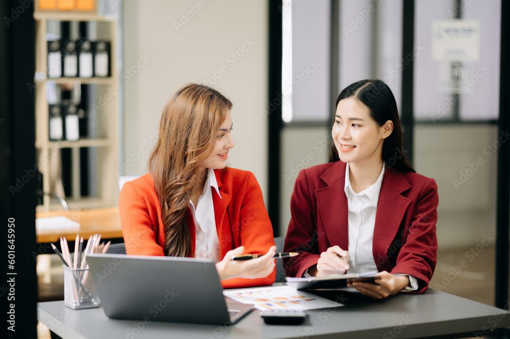 Two Asian businesswoman discuss investment project working and planning strategy with tablet laptop computer in office.