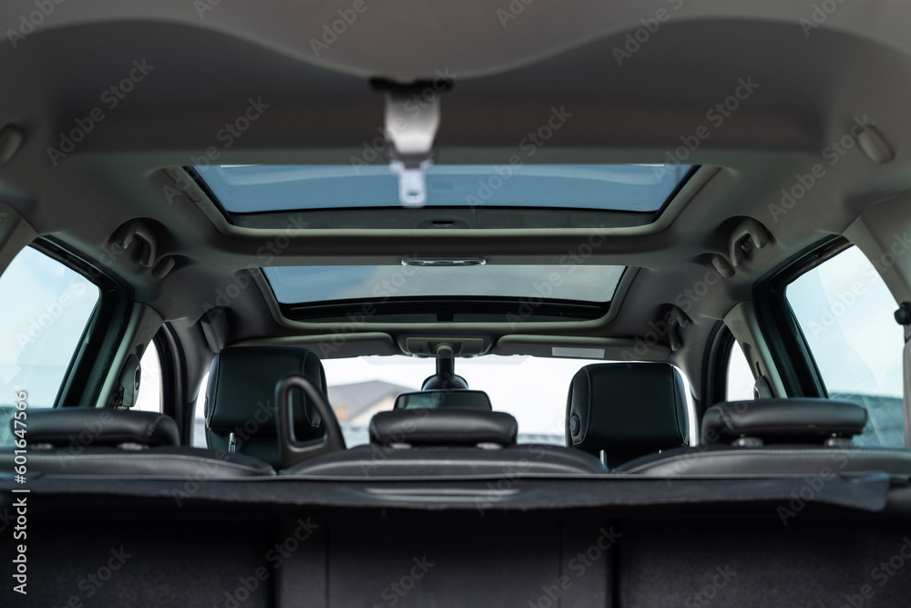 Panoramic glass sun roof in the modern car. Clean sunroof and view at the sky from the inside or car interior. The view from the empty car trunk with rear seats