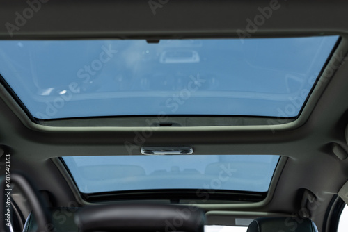 Panoramic glass sun roof in the modern car. Panoramic view inside car - double sunroof hatch with tinted glass. Sliding panoramic sunroof and luxurious leather seats