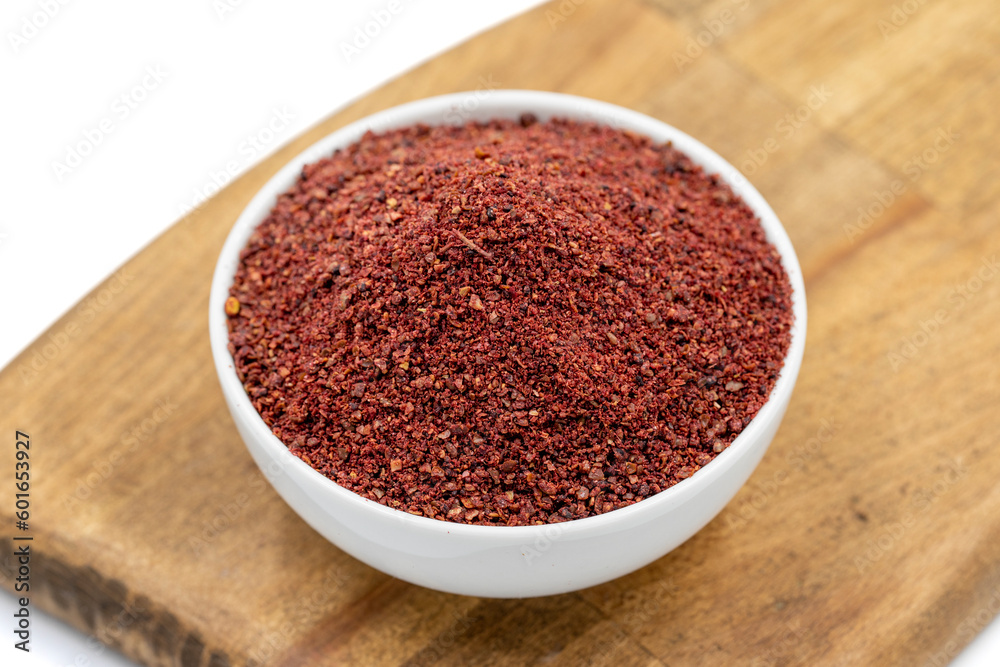 Sumac isolated on white background. Dried ground red Sumac powder spices in wooden bowl Sumac isolated on white background. Dried ground red Sumac powder spices in wooden bowl