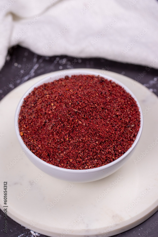 Sumac on dark background. Dried ground red Sumac powder spices in wooden bowl. Close up Sumac on dark background. Dried ground red Sumac powder spices in wooden bowl. Close up