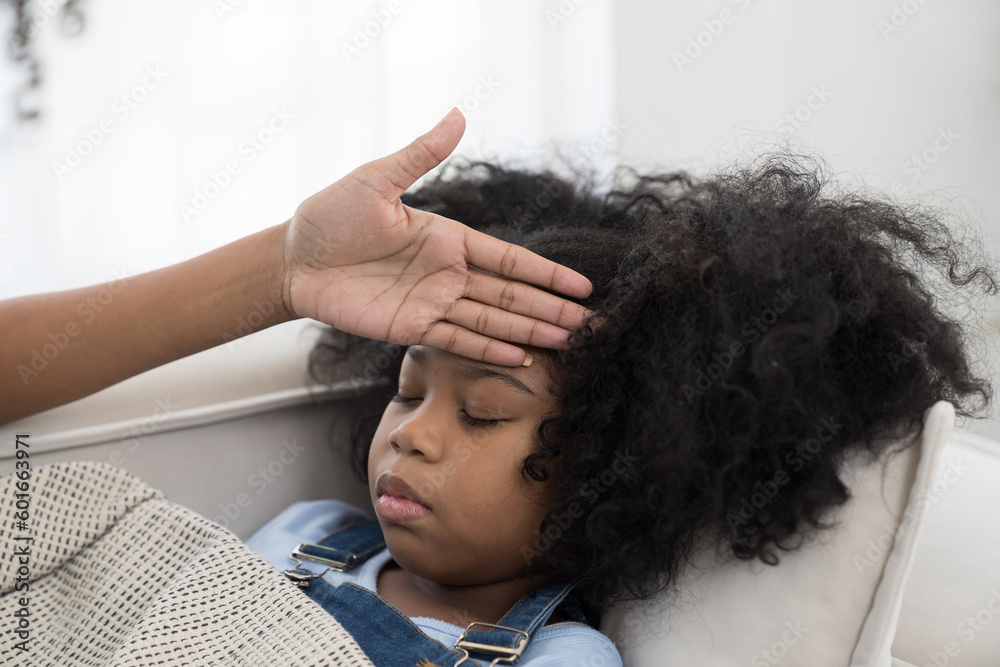 Naklejka premium Young female doctor or nurse taking care and checking temperature on forehead of child girl patient in hospital