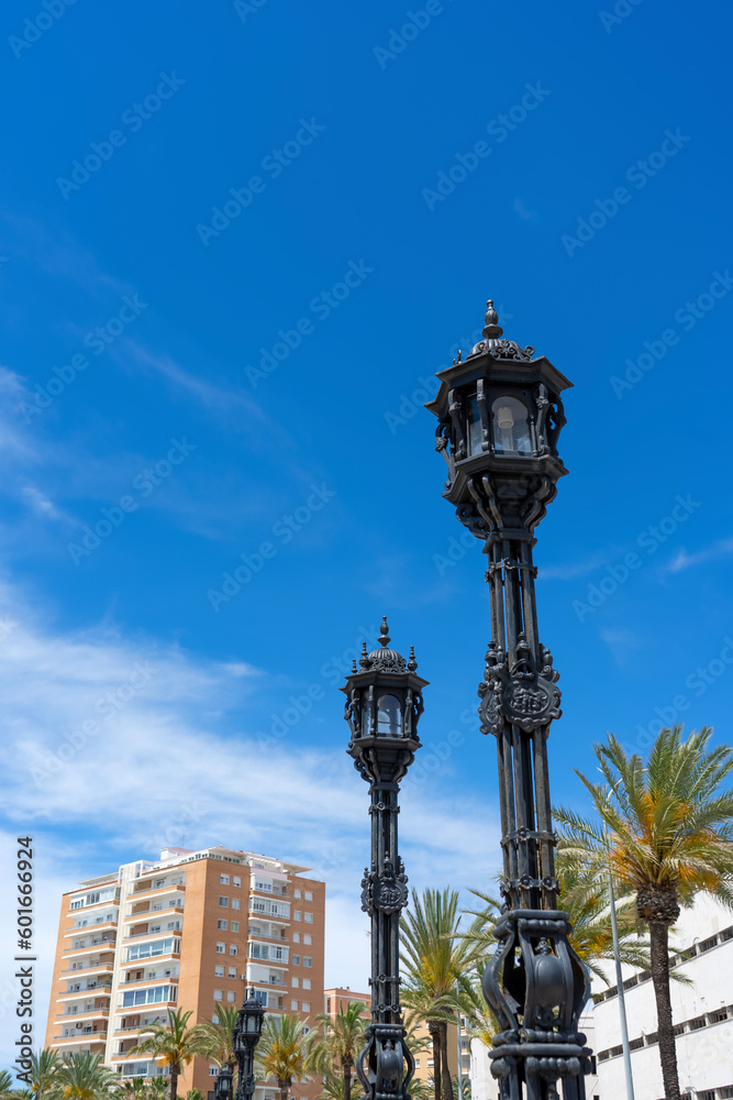 Street lamps on promenade in front of La Caleta beach in Cadiz, Spain on April 30, 2023
