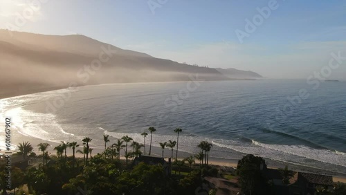 Aerial cinematic drone early morning sunrise stunning surf Santa Barbara Isla Vista California Ocean bay pier xgames spring green yellow blues gold forward pan up movement photo