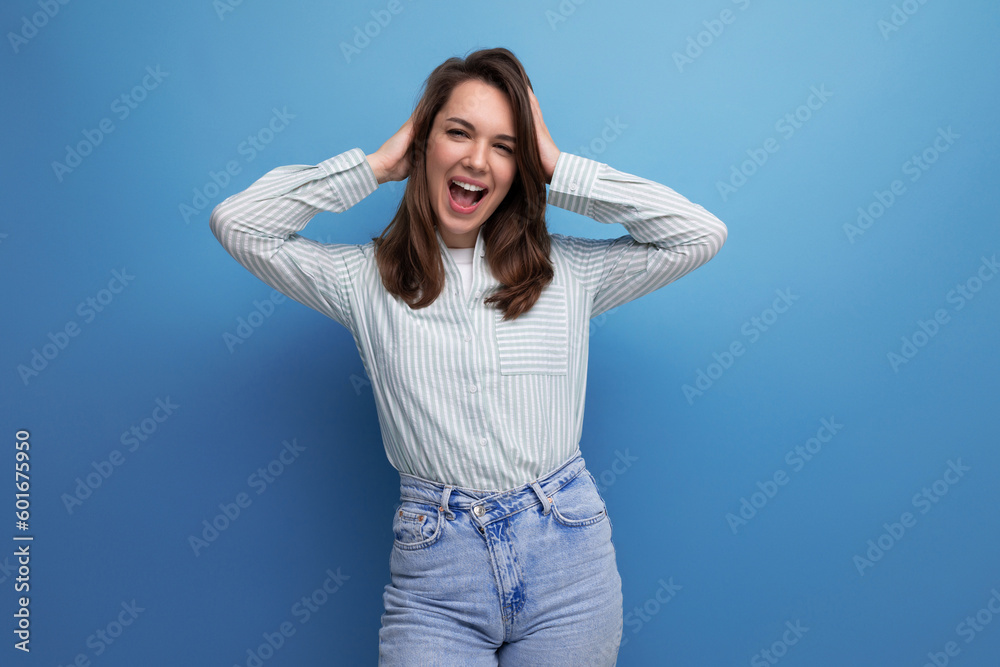 well-groomed young brunette lady dressed in a striped shirt and jeans smiling on a studio background well-groomed young brunette lady dressed in a striped shirt and jeans smiling on a studio background