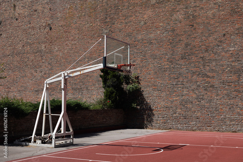 The basketball court in the park, next to the old brick wall.