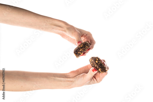 Healthy granola bar (muesli or cereal bar) isolated on white background. Muesli bar in females hands with red manicure. © jul_photolover