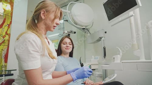 The dentist consults the patient and shows the woman Invisalign braces, transparent plastic removable aligners. Dentistry, dental clinic, orthodontics.
