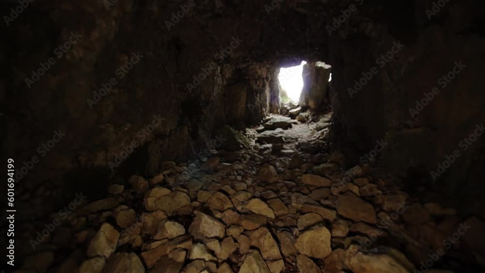 Floor of tunnel covered with stones and sunlight at end
