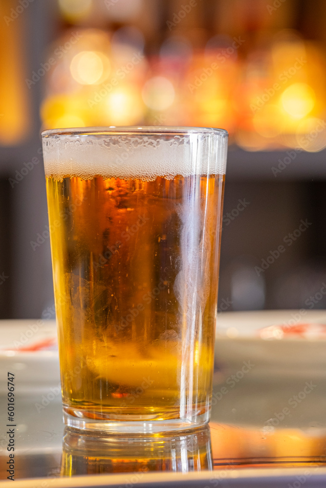 An appetizing and fresh draft beer served in a glass on the table of a bar terrace.
