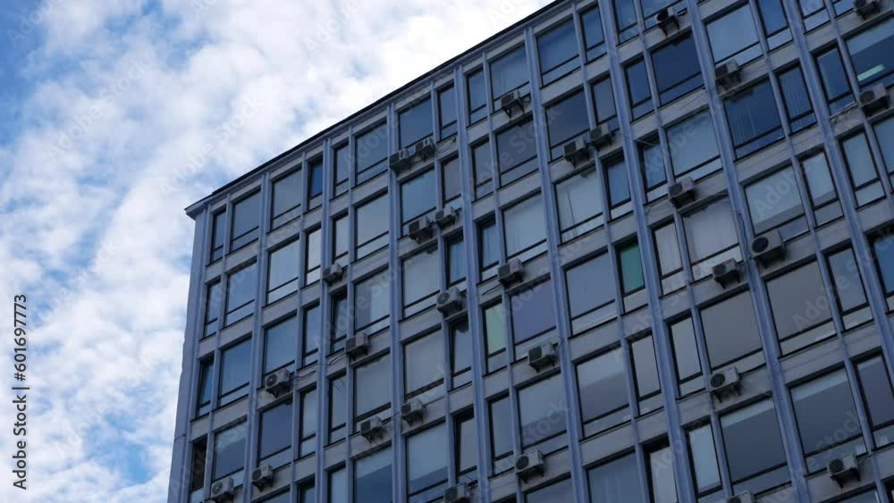 Static shooting of an office building with an active movement of clouds. The building is hung with air conditioning boxes. Static shooting of an office building with an active movement of clouds. The building is hung with air conditioning boxes.