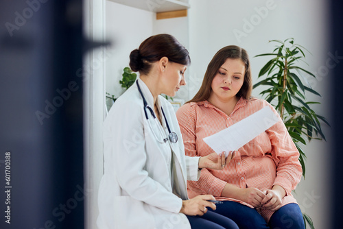 Obraz na płótnie An overweight woman is looking at a diet plan with her female nutritionist