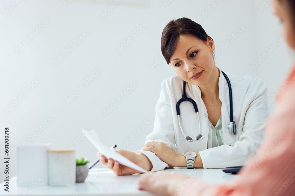 A serious female doctor sitting with a patient after examination at the clinic. A serious female doctor sitting with a patient after examination at the clinic.