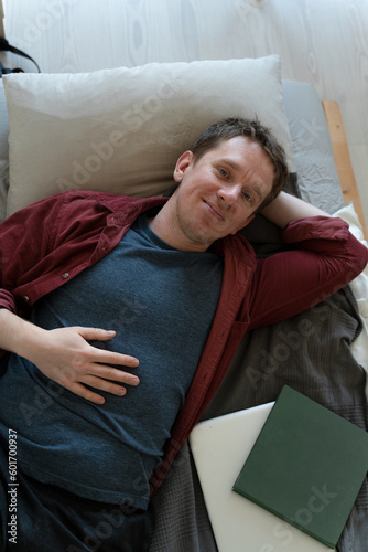 caucasian guy relaxing and daydreaming in bed at home. looking in the camera