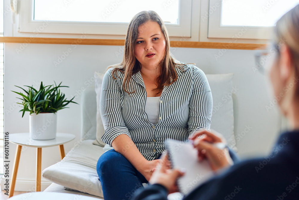 A sad overweight woman with an eating disorder talking with a female psychotherapist. - obrazy, fototapety, plakaty 