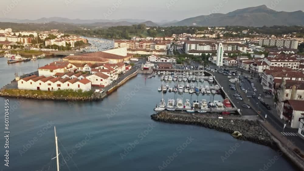 Aerial overview of fishing vessels and harbor buildings near confluence of canal and sea