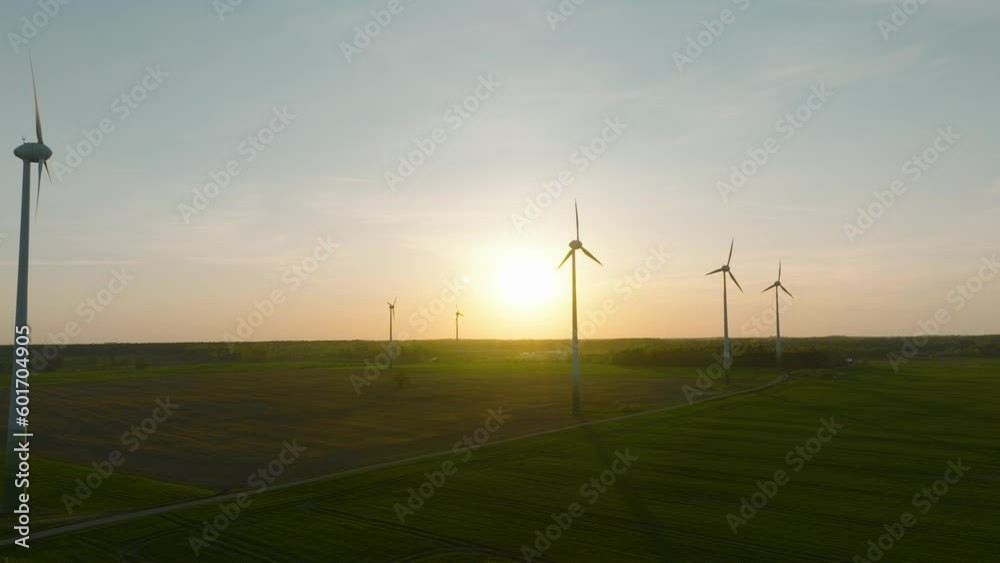 Aerial view of wind turbines generating renewable energy in the wind farm, green countryside landscape, vibrant sunny spring evening with golden hour light, wide drone dolly shot moving right Aerial view of wind turbines generating renewable energy in the wind farm, green countryside landscape, vibrant sunny spring evening with golden hour light, wide drone dolly shot moving right