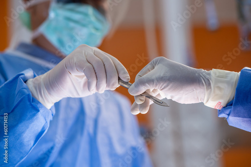 Team of surgery doctor in Operating Room hold hands scalpel surgical blade give to Surgeons During Operation. surgeons assistance in green gown coat give scalpel surgical blade to doctor