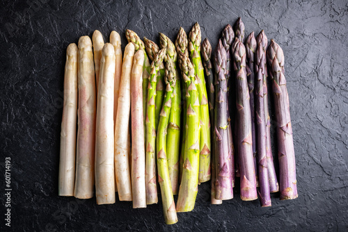 Top view of green, purple and white asparagus sprouts on black background closeup. Food photography