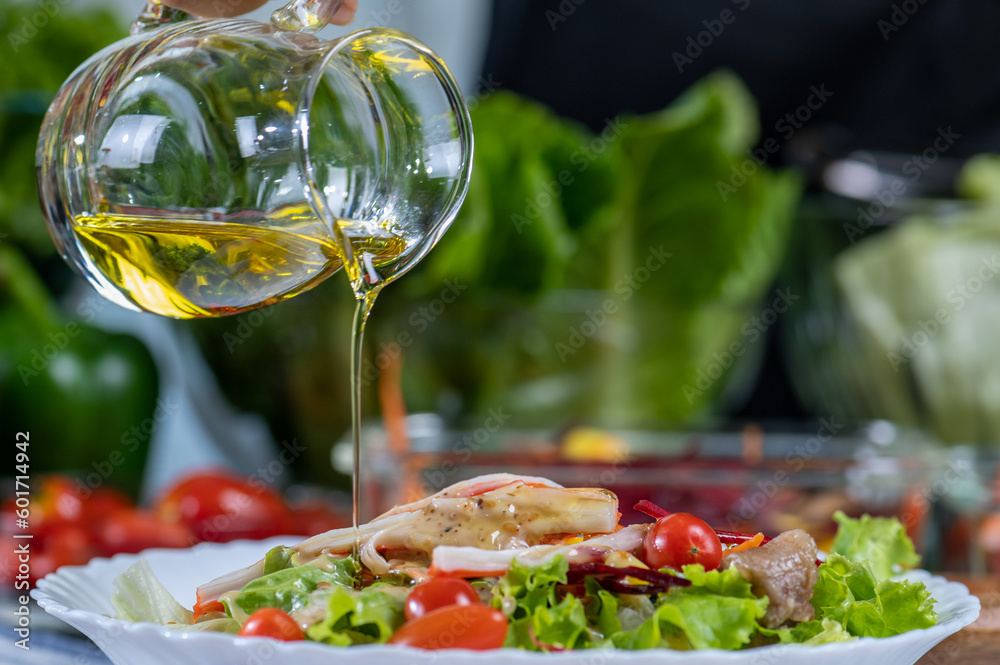 woman chef mix fresh baby cos salad and pour salad dressing in glass blow. Organic Vegetables mix all green salad In glass bowl. Breakfast fresh salad and clean vegetable.
