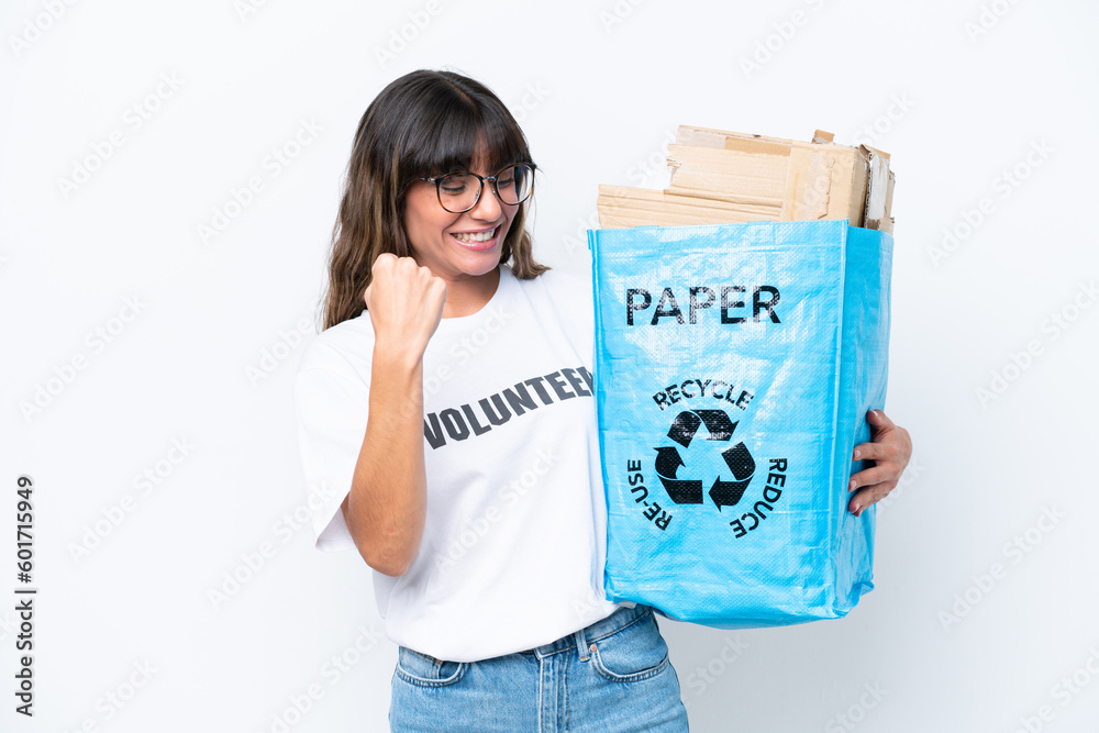 Young caucasian woman holding a recycling bag full of paper to recycle isolated on white background celebrating a victory Young caucasian woman holding a recycling bag full of paper to recycle isolated on white background celebrating a victory