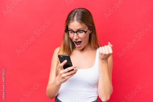 Young beautiful woman isolated on red background surprised and sending a message