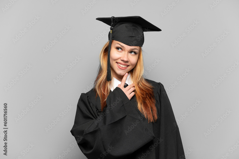 Young university graduate girl over isolated background looking up while smiling Young university graduate girl over isolated background looking up while smiling